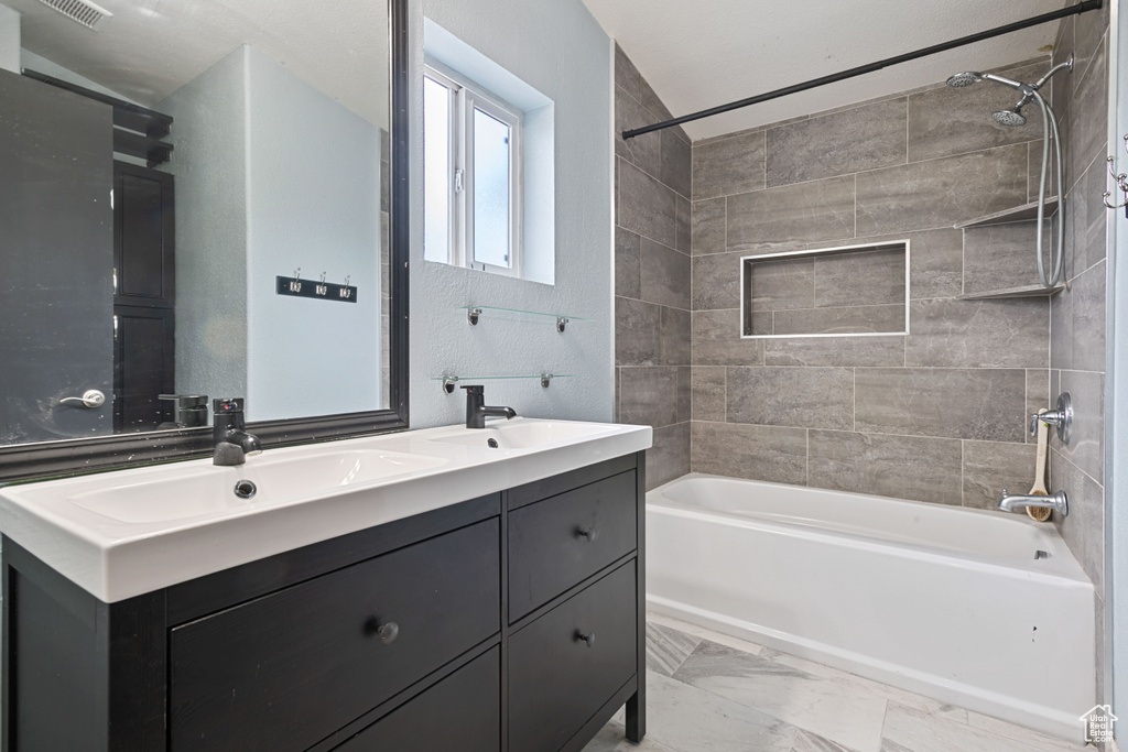 Bathroom with shower / bathtub combination, double vanity, and marble look tiles