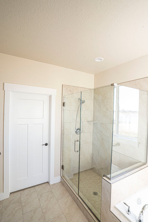 Bathroom featuring a tile shower, a bath, tile patterned floors, a textured ceiling, and recessed lighting