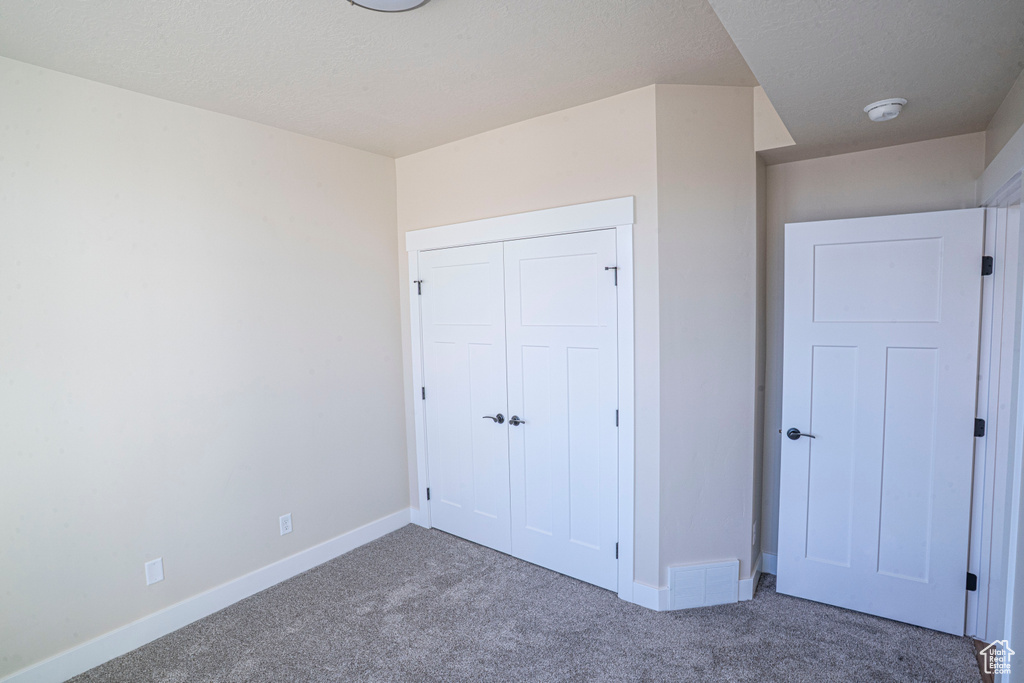 Unfurnished bedroom with carpet and a closet