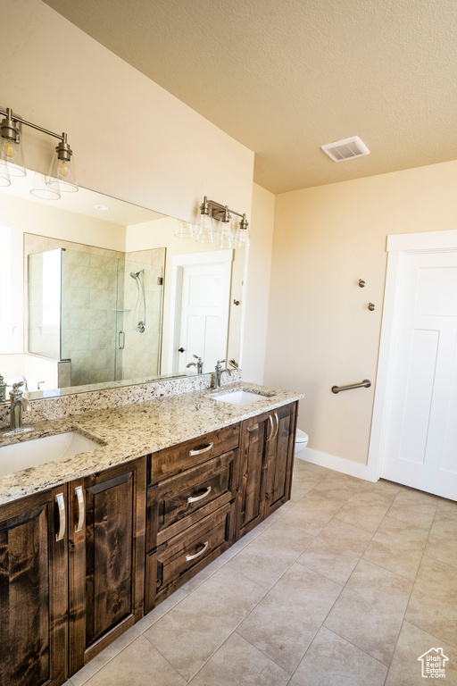 Bathroom featuring a shower stall, double vanity, tile patterned flooring, and a textured ceiling