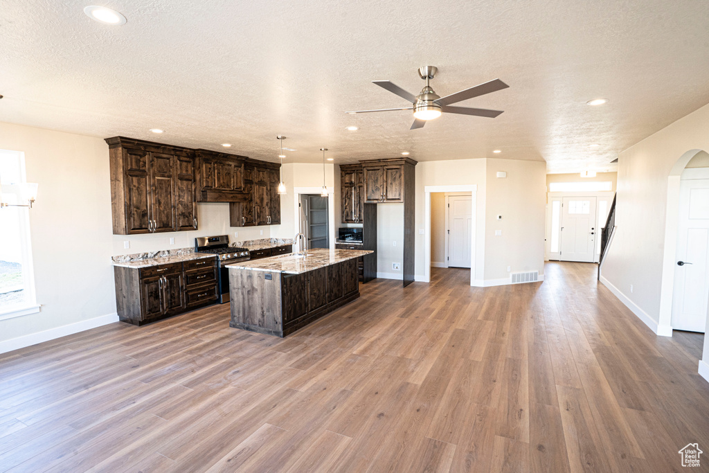 Kitchen featuring stainless steel appliances, ceiling fan, recessed lighting, dark brown cabinets, and a kitchen island with sink