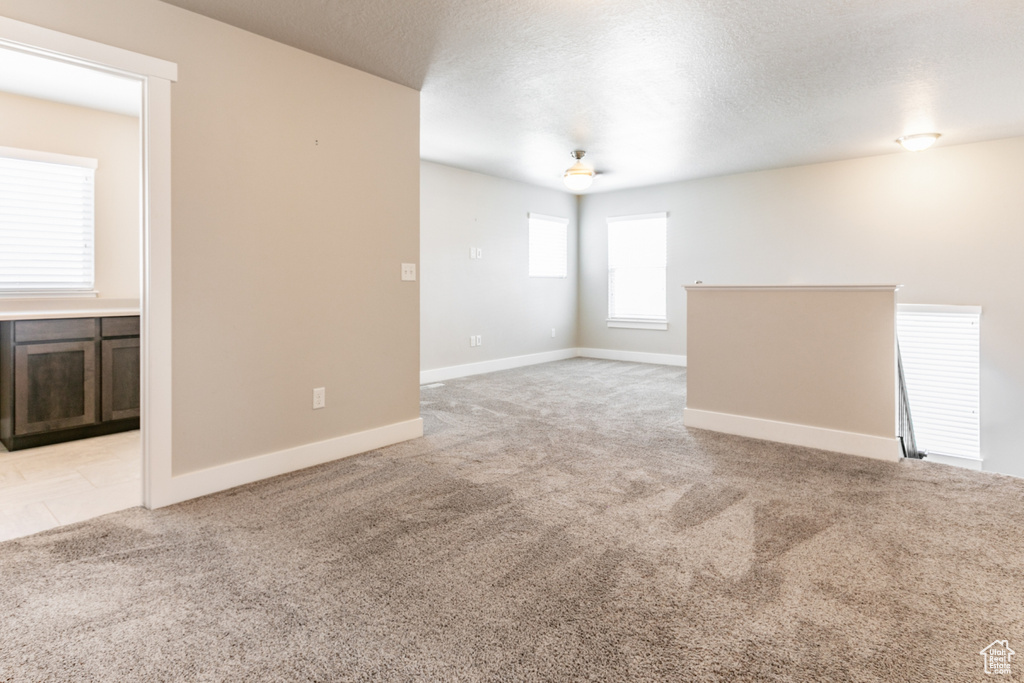 Carpeted empty room featuring baseboards and a textured ceiling