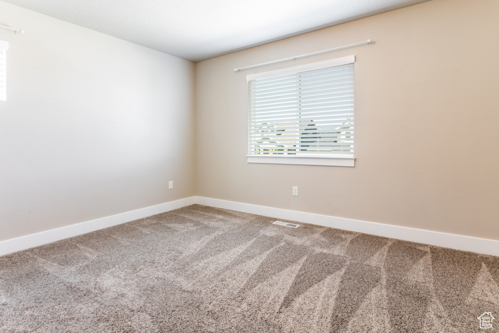 Carpeted spare room featuring baseboards