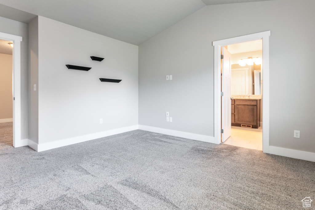 Unfurnished bedroom with carpet flooring, vaulted ceiling, and ensuite bathroom
