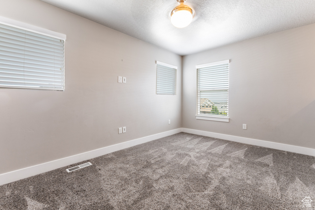 Empty room with carpet and a textured ceiling