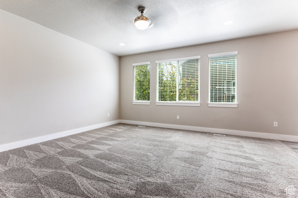 Carpeted empty room with a textured ceiling and recessed lighting