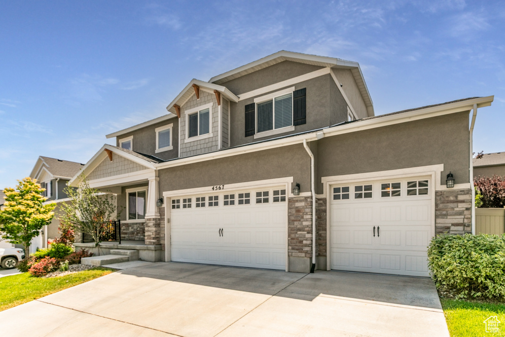 View of front of property with stone siding, stucco siding, and concrete driveway