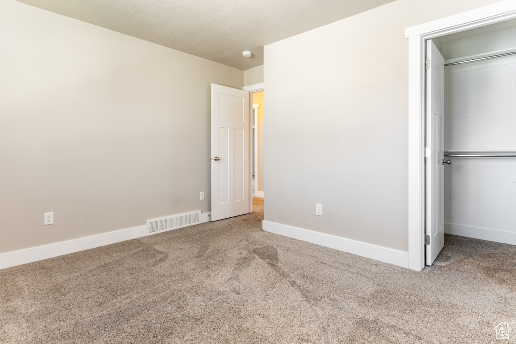 Unfurnished bedroom with carpet flooring, a closet, and a spacious closet