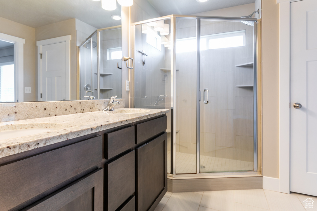 Bathroom featuring double vanity, a shower stall, and tile patterned floors