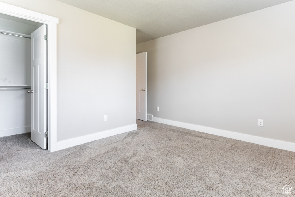 Unfurnished bedroom featuring carpet flooring, a closet, and a walk in closet
