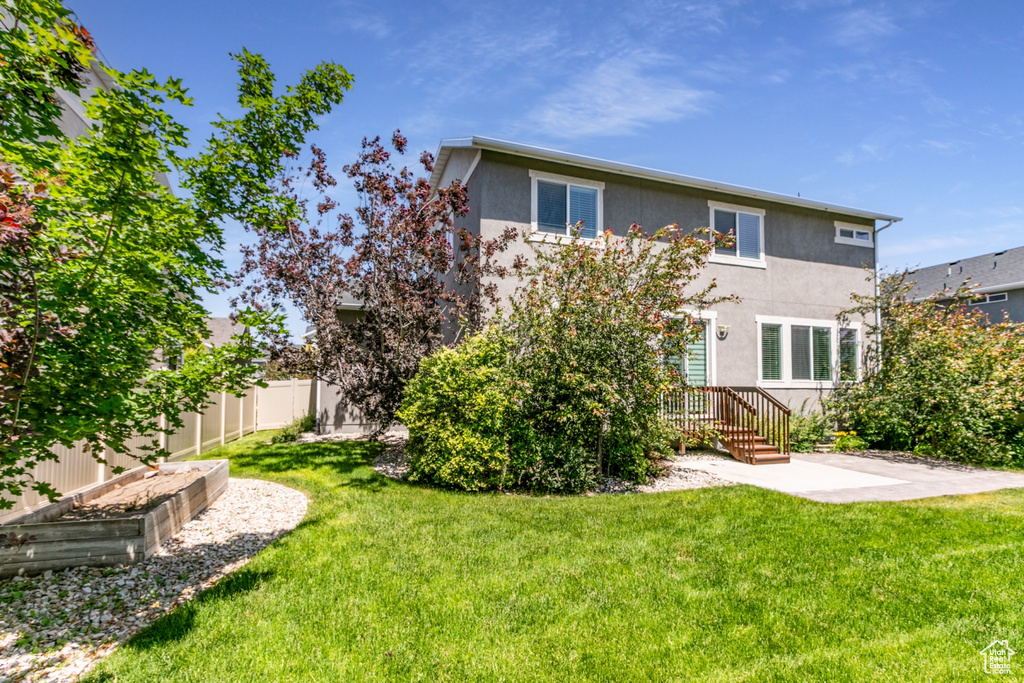 Rear view of house with stucco siding, a vegetable garden, and a patio