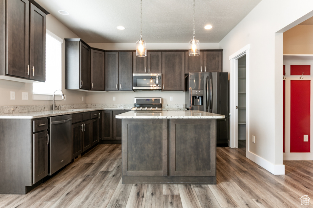 Kitchen featuring stainless steel appliances, dark brown cabinets, light wood-style flooring, a center island, and recessed lighting