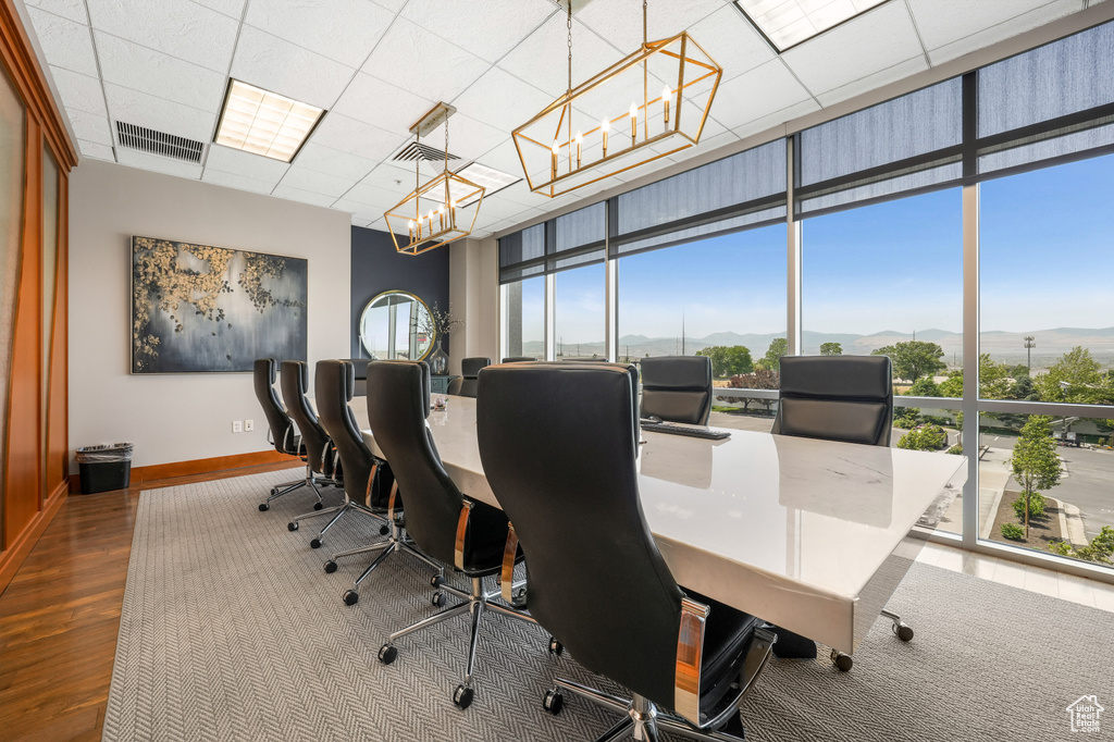 Office space with a chandelier, a mountain view, plenty of natural light, wood finished floors, and expansive windows