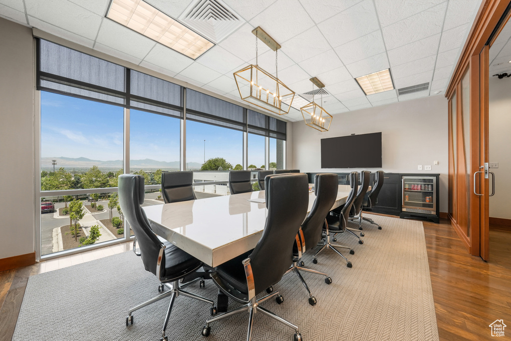 Office space with wood finished floors, plenty of natural light, a mountain view, a wall of windows, and a chandelier