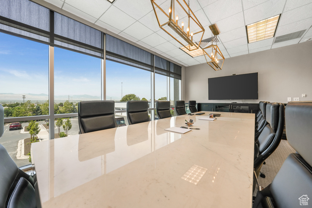 Home office featuring a chandelier, healthy amount of natural light, floor to ceiling windows, and a paneled ceiling
