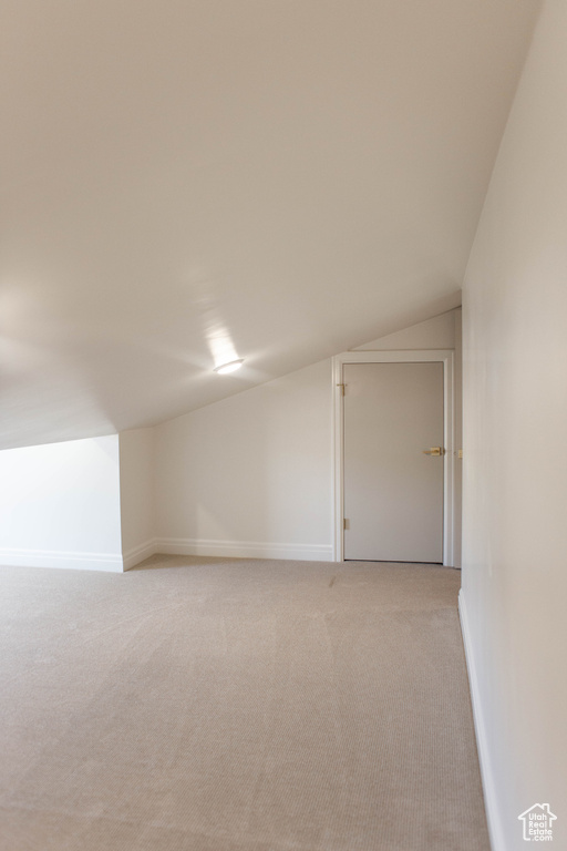 Bonus room featuring vaulted ceiling and light colored carpet