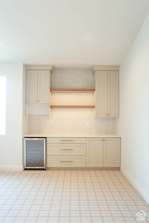 Kitchen featuring beverage cooler, decorative backsplash, light countertops, and open shelves