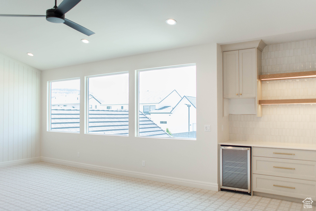Kitchen featuring beverage cooler, light countertops, decorative backsplash, plenty of natural light, and recessed lighting