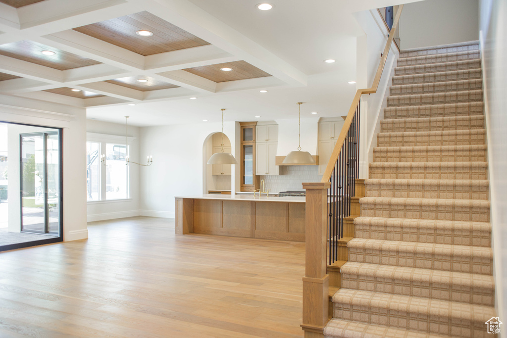 Staircase featuring wood finished floors, coffered ceiling, beam ceiling, and recessed lighting