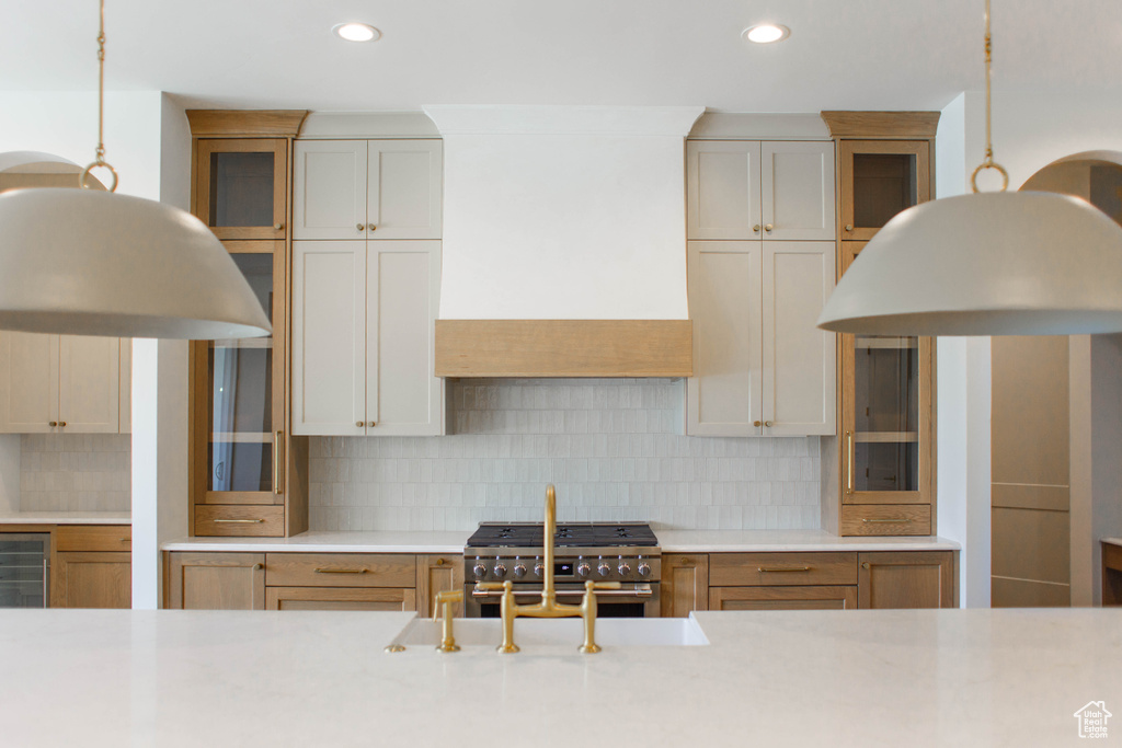 Kitchen featuring high end stainless steel range, premium range hood, light countertops, glass insert cabinets, and recessed lighting