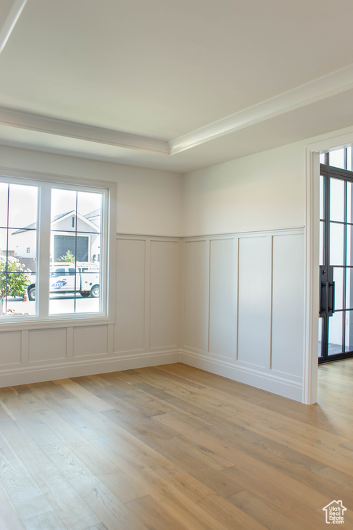 Spare room with a decorative wall, light wood-type flooring, plenty of natural light, and a wainscoted wall