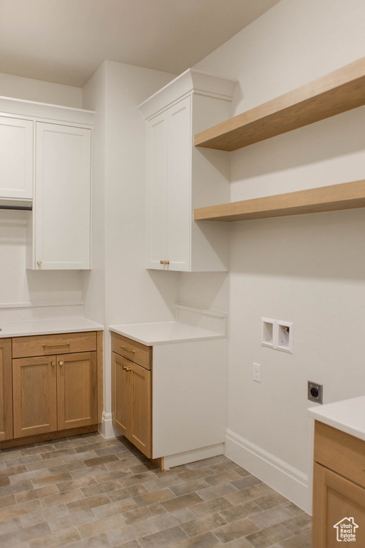 Laundry area with electric dryer hookup, hookup for a washing machine, and cabinet space