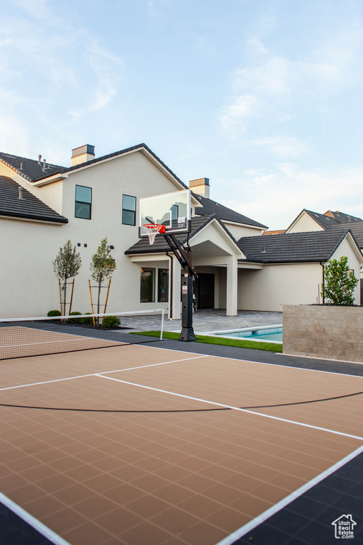 View of tennis court with basketball hoop and an outdoor pool