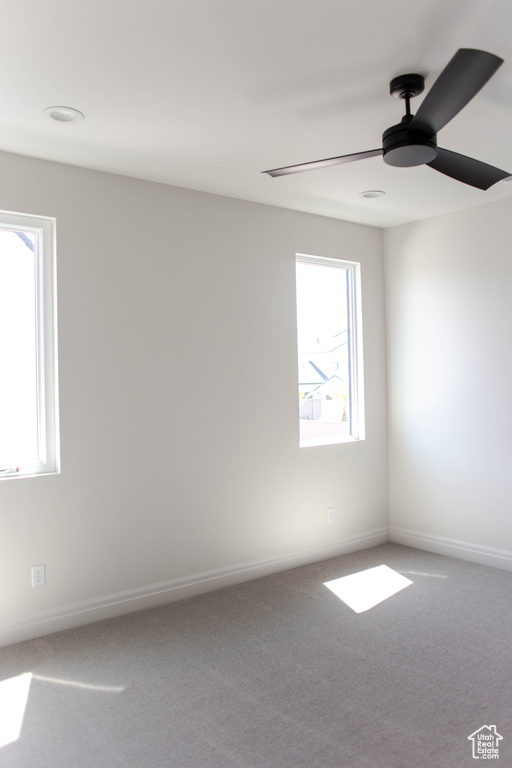 Carpeted empty room with ceiling fan and healthy amount of natural light