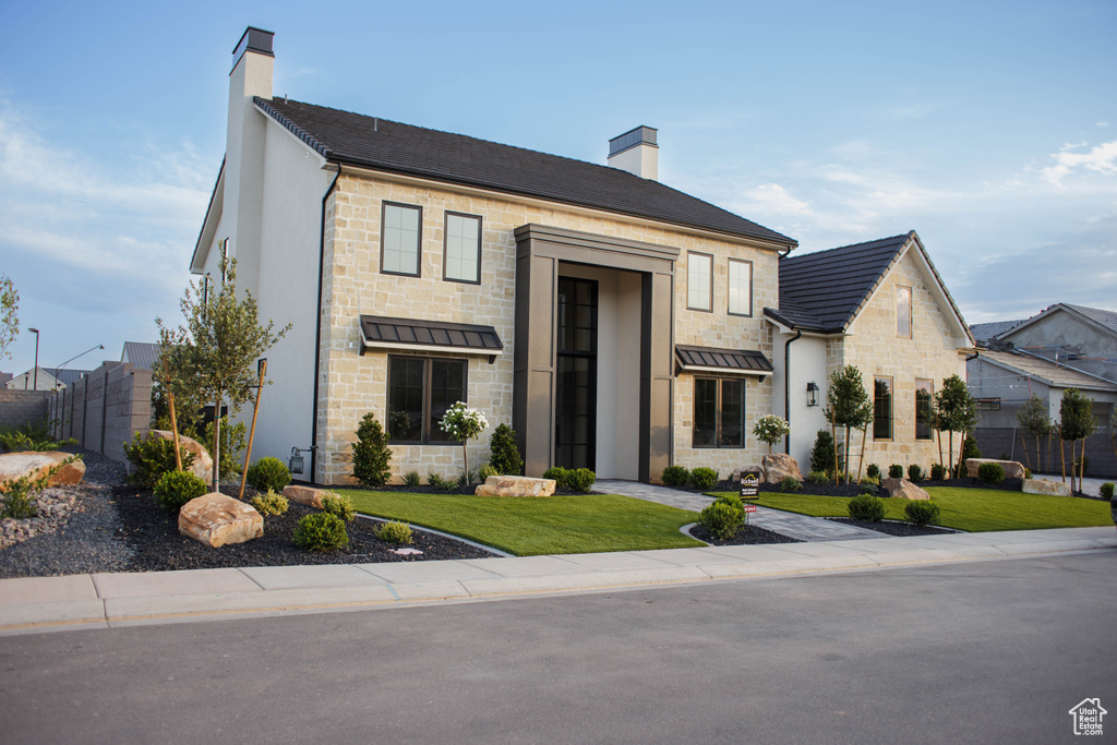 View of front facade with a chimney, stone siding, and a standing seam roof