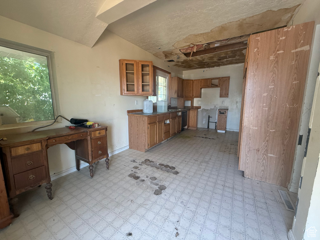 Kitchen with light flooring, brown cabinets, and glass insert cabinets