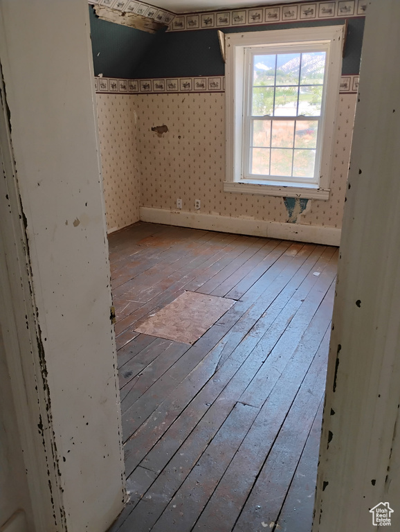 Unfurnished bedroom with wood-type flooring and wallpapered walls