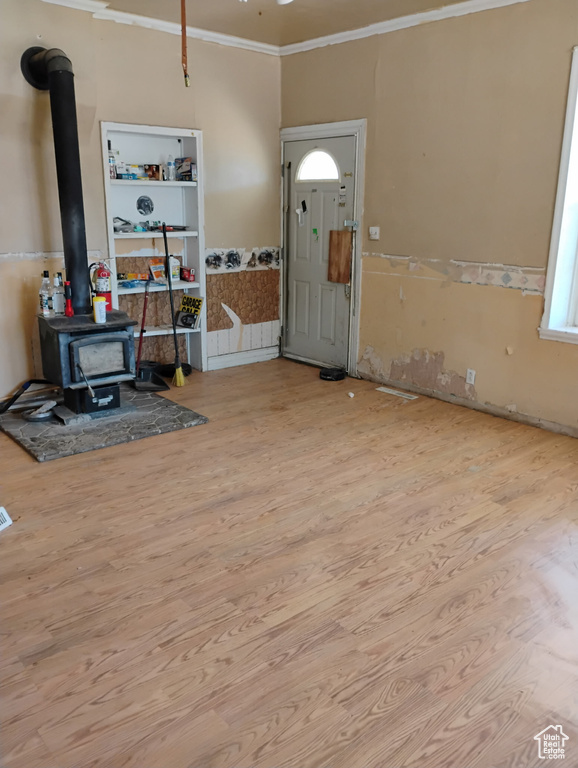 Entrance foyer featuring wood finished floors, ornamental molding, and a wood stove