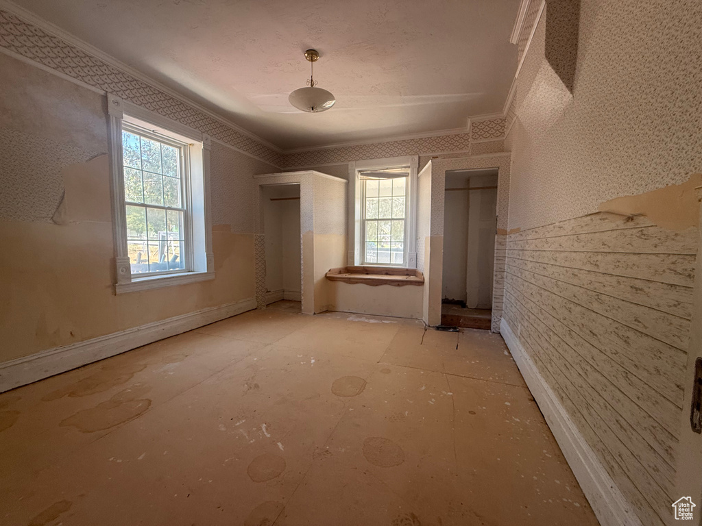 Spare room featuring ornamental molding and wallpapered walls