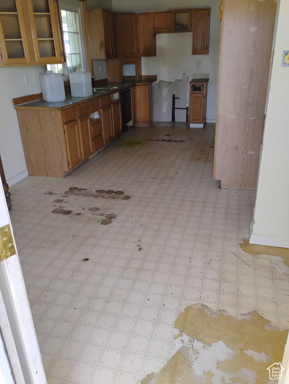 Kitchen featuring black dishwasher, light floors, brown cabinets, and glass insert cabinets