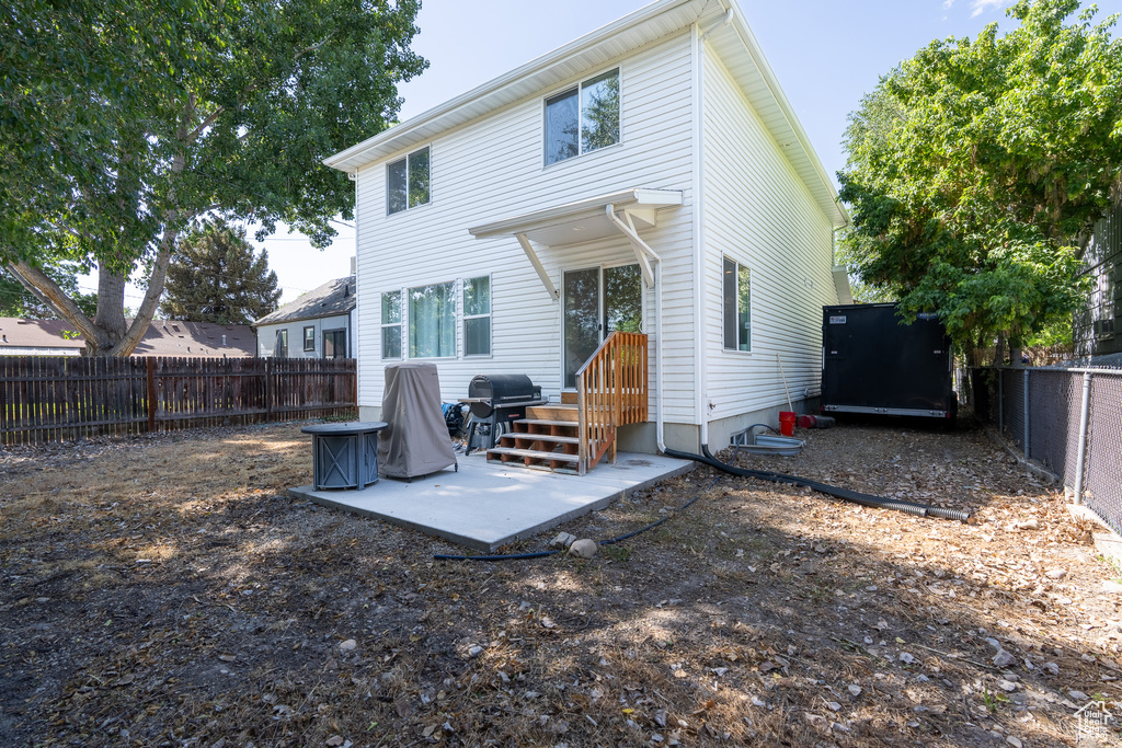 Rear view of house with a fenced backyard and a patio area