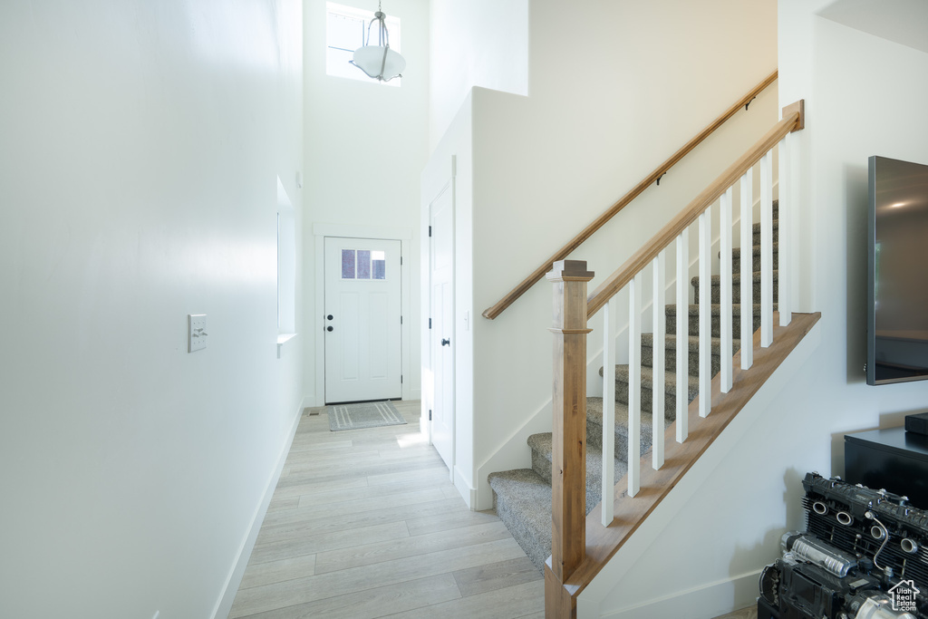 Stairway with wood finished floors and a towering ceiling