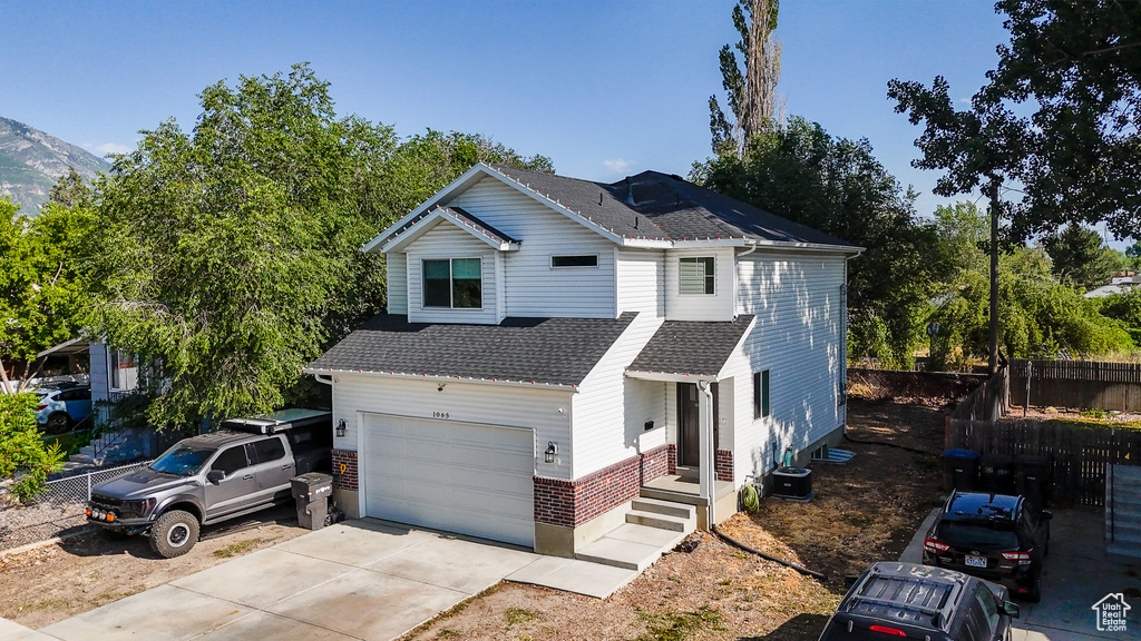 Traditional-style home featuring a garage, roof with shingles, concrete driveway, and brick siding