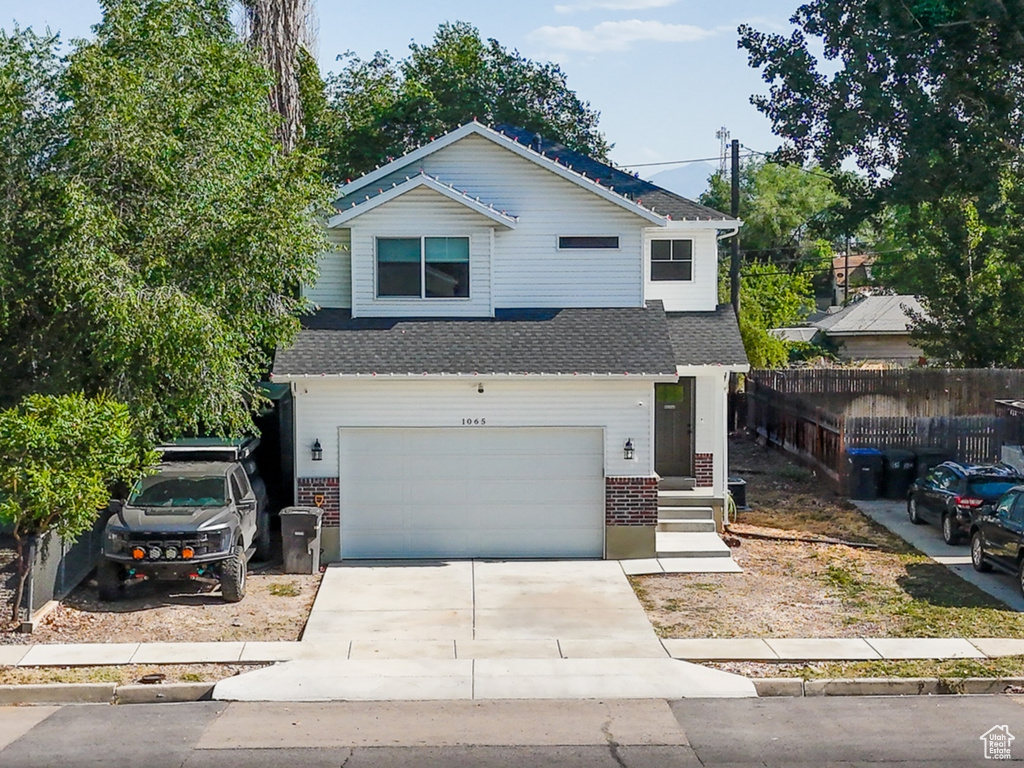 View of front of house featuring an attached garage, concrete driveway, and brick siding