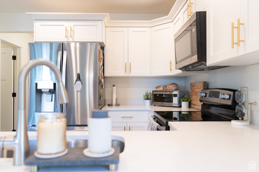 Kitchen with stainless steel appliances, light countertops, and white cabinetry