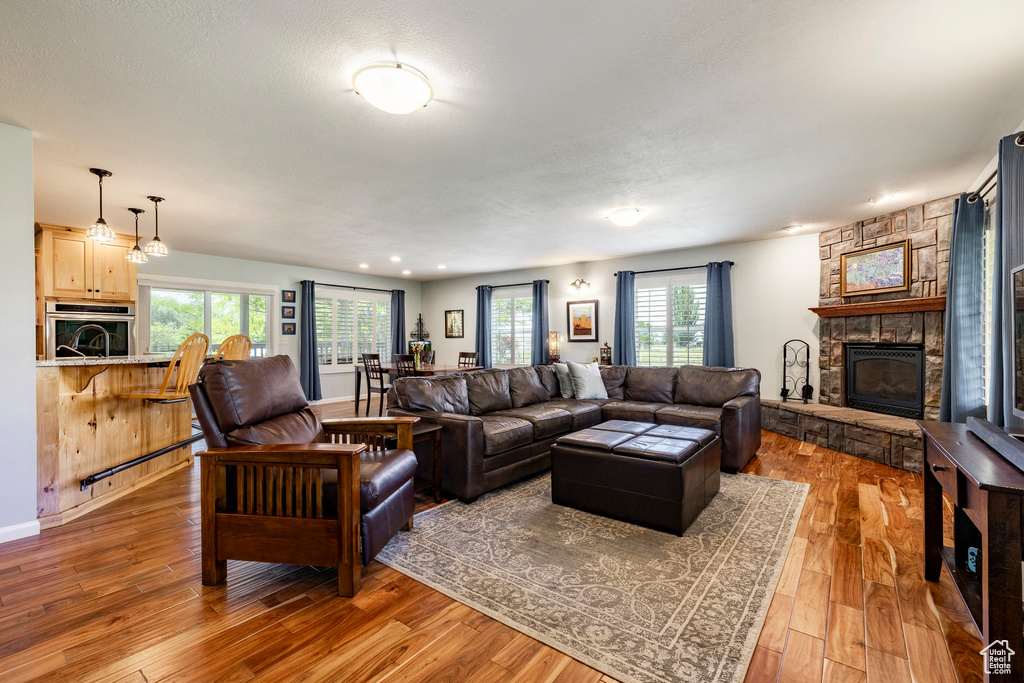Living area with a stone fireplace, light wood-style floors, and recessed lighting