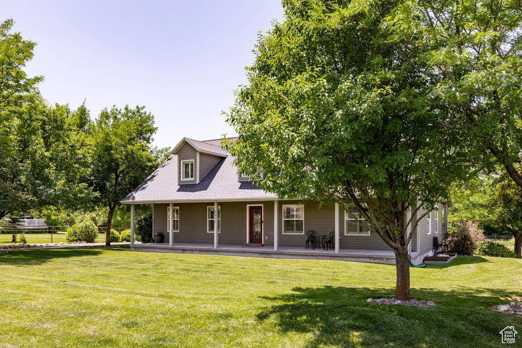 Back of house with a lawn, a porch, and roof with shingles