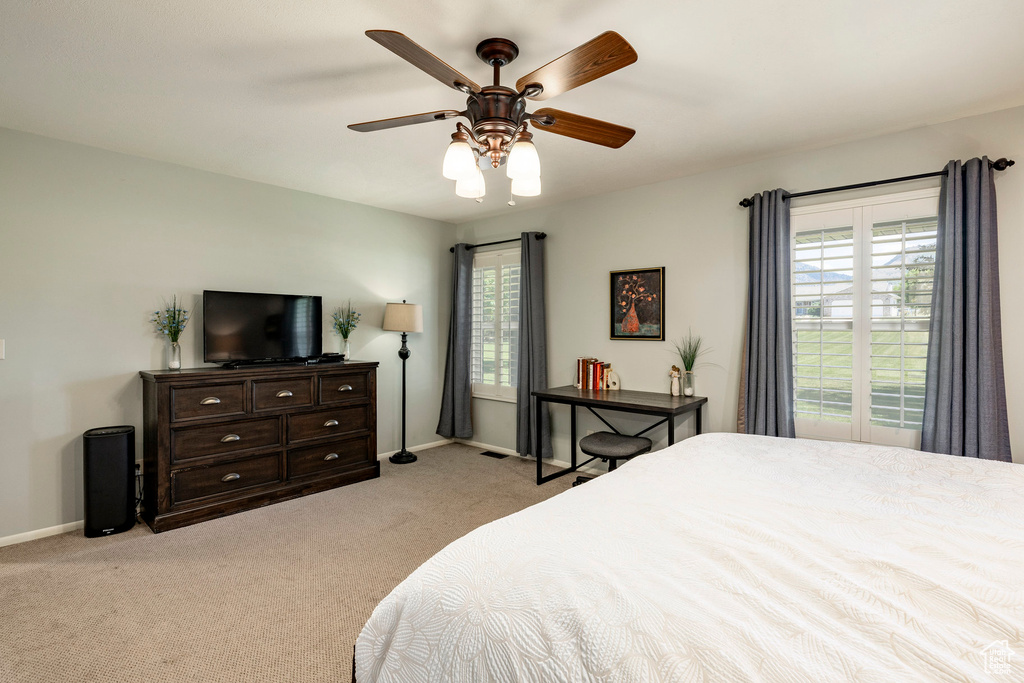 Carpeted bedroom featuring multiple windows and a ceiling fan