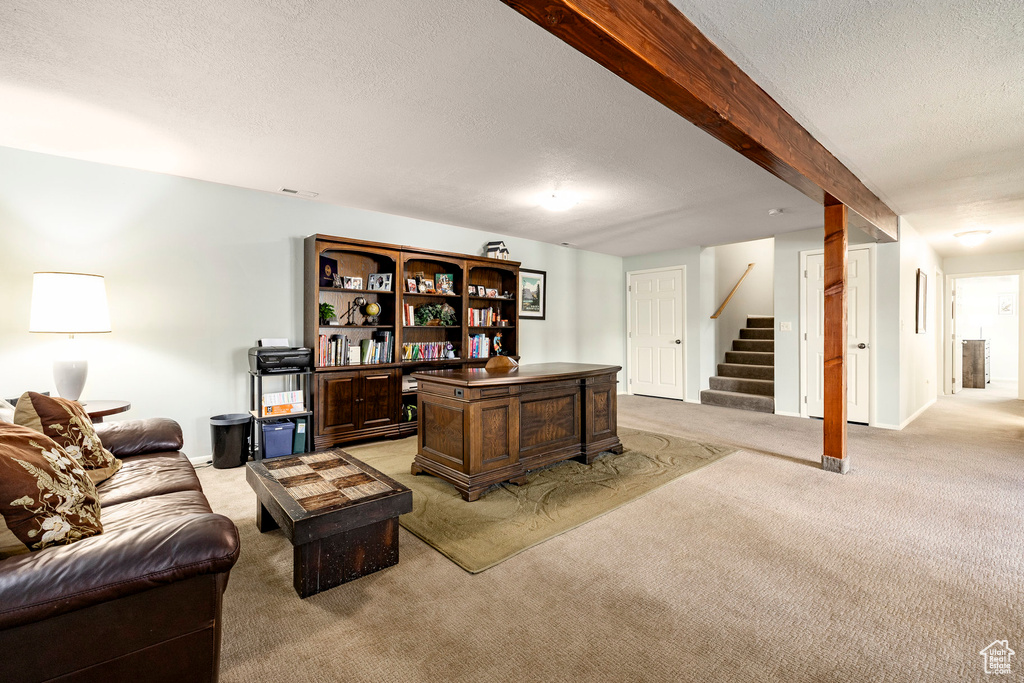Living area with light carpet, a textured ceiling, and stairway
