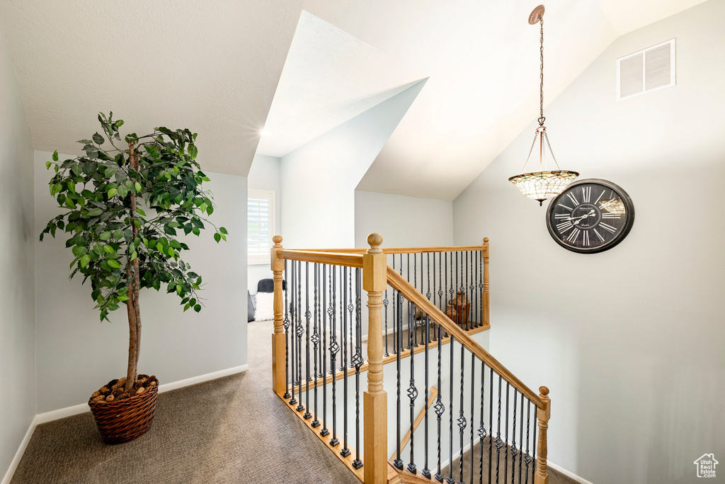 Hall with an upstairs landing, carpet flooring, and lofted ceiling