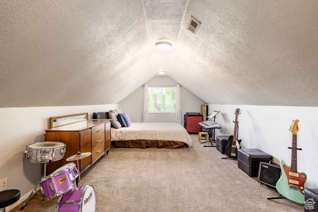 Bedroom featuring a textured ceiling, light colored carpet, and vaulted ceiling