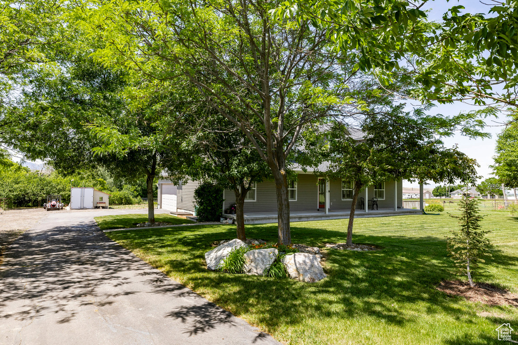 Obstructed view of property featuring asphalt driveway, a front lawn, and covered porch