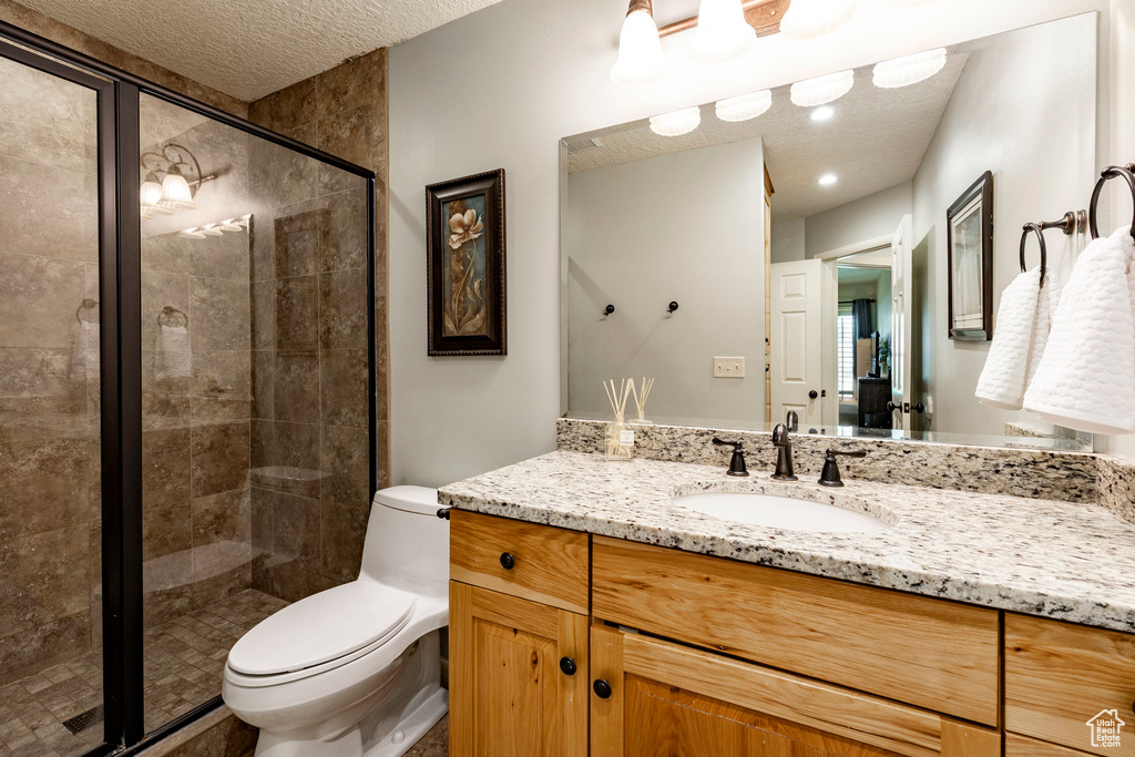 Full bath featuring vanity, a textured ceiling, and a shower stall