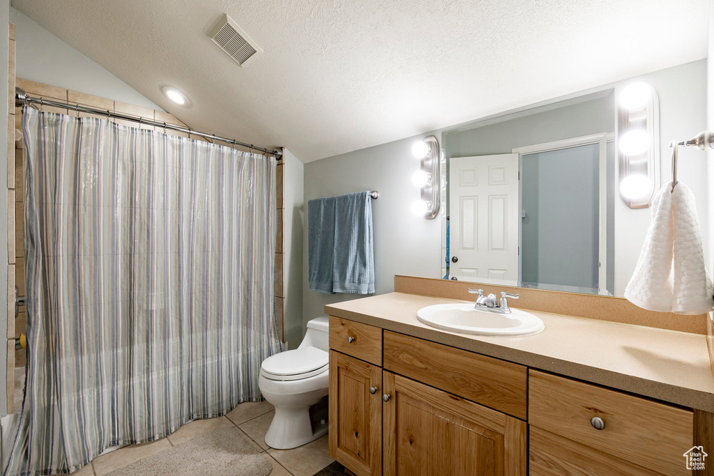 Full bathroom with vanity, tile patterned floors, lofted ceiling, a textured ceiling, and shower / bath combo with shower curtain
