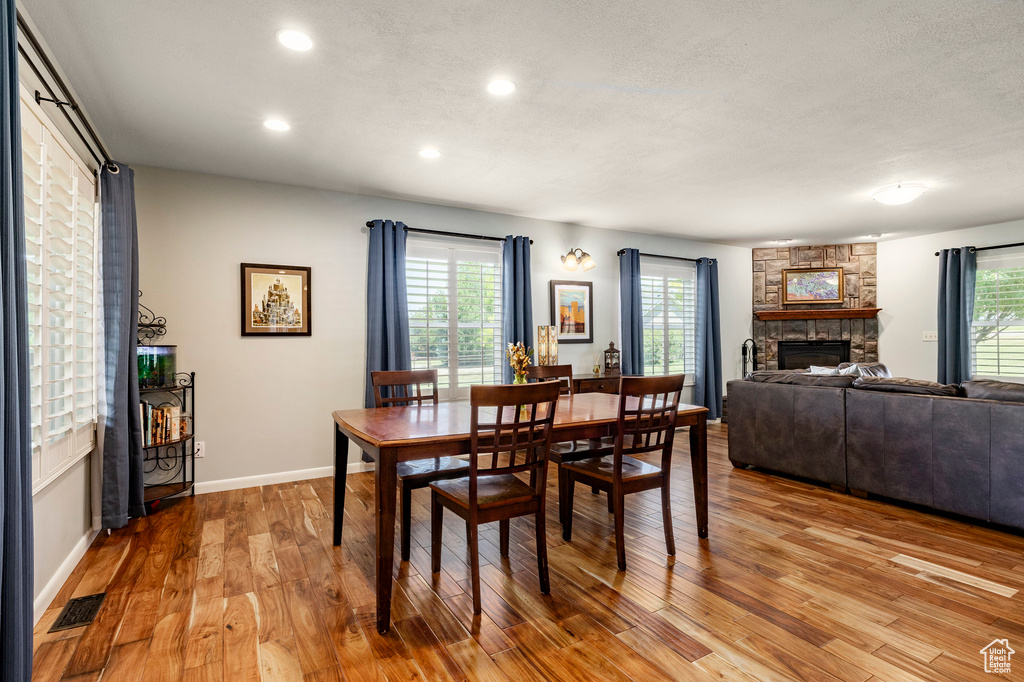 Dining room with a fireplace, light wood finished floors, recessed lighting, and healthy amount of natural light
