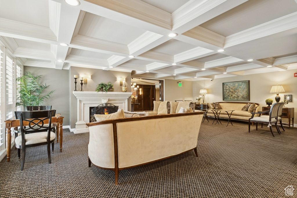 Living room with dark colored carpet, beam ceiling, a warm lit fireplace, coffered ceiling, and ornamental molding
